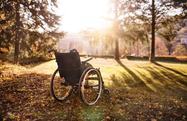 An empty wheelchair on a grass in park at sunset. - HPIF26716