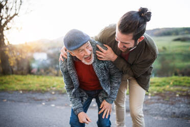 Ein junger Mann und sein älterer Vater bei einem Spaziergang in der Natur, lachend. - HPIF26729