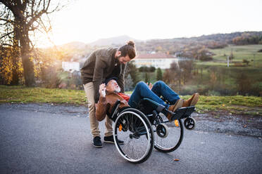Ein junger Mann und sein älterer Vater im Rollstuhl machen einen Spaziergang durch die Stadt und haben Spaß. - HPIF26732