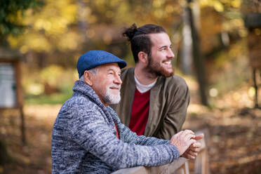 Ein älterer Vater und sein Sohn auf einem Spaziergang in der Natur, stehend und im Gespräch. - HPIF26748