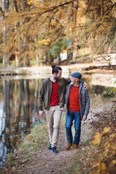Ein älterer Vater und sein kleiner Sohn gehen in der Natur spazieren und unterhalten sich. - HPIF26756