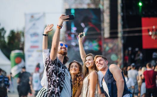 Eine Gruppe junger Freunde auf einem Sommerfest macht ein Selfie mit ihrem Smartphone, von vorne gesehen - HPIF26797