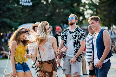 Ein Porträt einer Gruppe junger Freunde, die auf einem Sommerfest tanzen, in der Vorderansicht. - HPIF26802