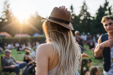 Rückansicht einer jungen Frau mit Hut auf einem Sommerfest oder im Campingurlaub. - HPIF26820