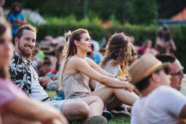 Eine Gruppe fröhlicher junger Freunde sitzt bei einem Sommerfest auf dem Boden. - HPIF26826
