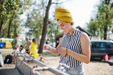 Junge Frau auf einem Sommerfest, die sich morgens an einem Waschbecken wäscht. - HPIF26861