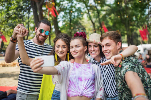 Eine Gruppe Jugendlicher, die auf einem Sommerfest ein Selfie mit ihren Smartphones macht - HPIF26876