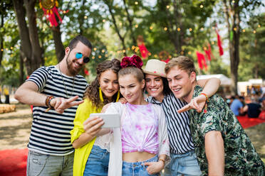 Eine Gruppe junger Freunde hält einen Moment auf einem Sommerfest fest und macht ein Selfie mit ihrem Smartphone - HPIF26877