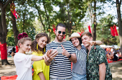 Eine Gruppe junger Freunde hält einen lustigen Moment auf einem Sommerfest mit einem Selfie auf ihrem Smartphone fest - HPIF26878