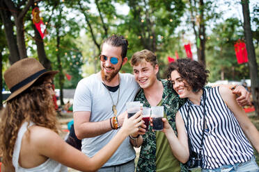 A group of young friends with drinks at summer festival, standing. - HPIF26900