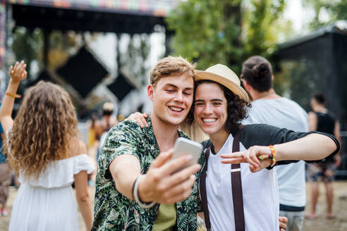 Lächelndes Paar hält Erinnerungen an das Sommerfest mit einem Selfie vor der Kameralinse fest - HPIF26906