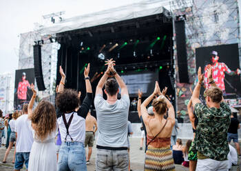 Rückansicht einer Gruppe nicht erkennbarer junger Freunde, die auf einem Sommerfest tanzen. - HPIF26921