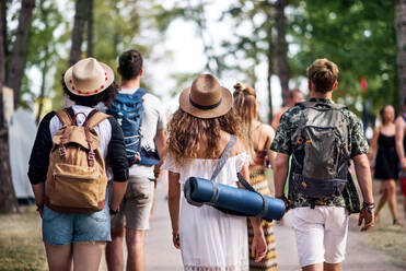 Rückansicht einer Gruppe junger Freunde mit Rucksack und Matte auf einem Sommerfest. - HPIF26932