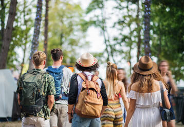 Rückansicht einer Gruppe junger Freunde mit Rucksack und Matte auf einem Sommerfest. - HPIF26935