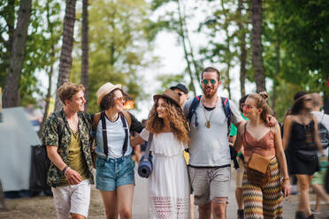 Vorderansicht einer Gruppe junger Freunde mit Rucksack und Matte, die auf einem Sommerfest spazieren gehen. - HPIF26936