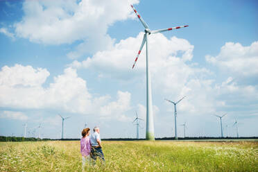 Ein älteres Ehepaar, das auf einem Feld in einem Windpark spazieren geht. Platz kopieren. - HPIF26978