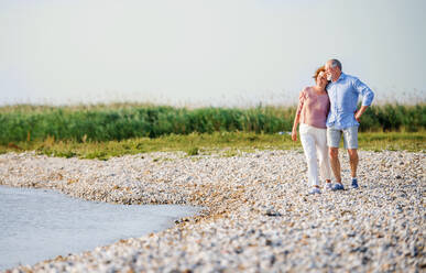 Ein älteres Ehepaar, das im Urlaub am See spazieren geht. Kopierraum. - HPIF26981