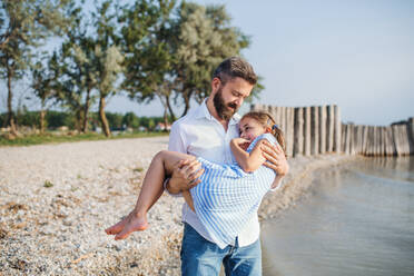 Ein reifer Vater mit seiner kleinen Tochter im Urlaub am See, beim Spazierengehen. - HPIF26983