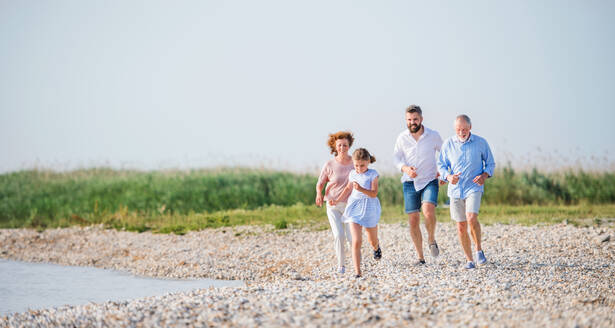 Eine Mehrgenerationenfamilie im Urlaub auf einem Spaziergang am See, beim Laufen. - HPIF27022