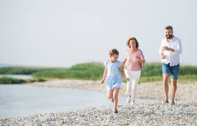 A multigeneration family on a holiday walking by the lake, running. - HPIF27023