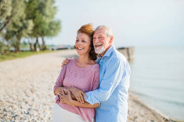 Vorderansicht eines älteren Paares im Urlaub bei einem Spaziergang am See, das sich umarmt. - HPIF27033