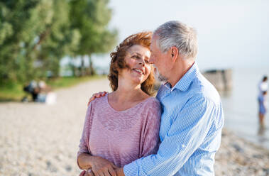A senior couple on a holiday on a walk by the lake, hugging. - HPIF27034