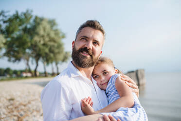 Seitenansicht von Vater und kleiner Tochter im Urlaub am See oder Meer. - HPIF27040