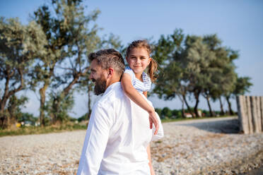 Ein reifer Vater mit seiner kleinen Tochter im Urlaub am See, beim Spazierengehen. - HPIF27042