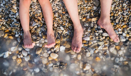 Draufsicht auf nackte Füße im Wasser von Vater und Kind im Urlaub am See. - HPIF27043