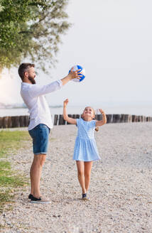 Ein reifer Vater und eine kleine Tochter im Urlaub, die am See oder am Meer spielen. - HPIF27053