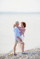 A senior couple on a holiday on a walk by the lake, hugging. - HPIF27054