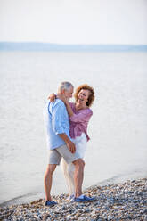 Vorderansicht eines älteren Paares im Urlaub bei einem Spaziergang am See, das sich umarmt. - HPIF27055
