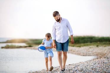 Ein reifer Vater und seine kleine Tochter im Urlaub, die am See oder am Meer spazieren gehen. - HPIF27058