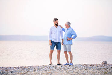 Älterer Vater und erwachsener Sohn stehen am See und unterhalten sich. Platz kopieren. - HPIF27062