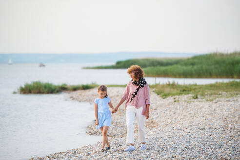 A small girl with grandmother on a holiday by the lake, walking and talking. - HPIF27066
