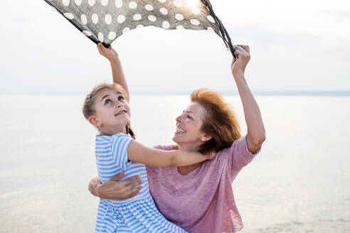 Ein kleines Mädchen mit seiner Großmutter im Urlaub am See, das sich amüsiert. - HPIF27069