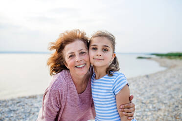 A small girl with grandmother on a holiday by the lake, looking at camera. - HPIF27071