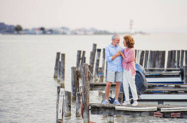 Verliebtes älteres Paar im Urlaub, das am See steht und sich unterhält. - HPIF27072