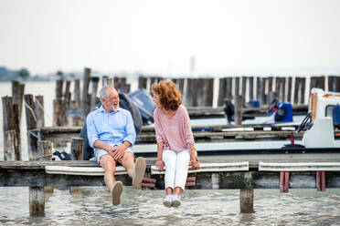 Verliebtes älteres Paar im Urlaub, das am See sitzt und sich unterhält. - HPIF27073