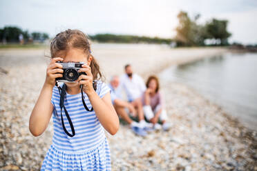 Vorderansicht eines kleinen Mädchens mit Kamera im Urlaub mit der Familie am See, das Fotos macht. - HPIF27084