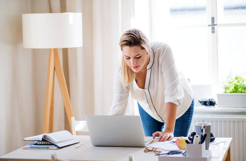 Junge Frau Architektin mit Laptop stehen am Schreibtisch drinnen im Büro zu Hause, arbeiten. - HPIF27102