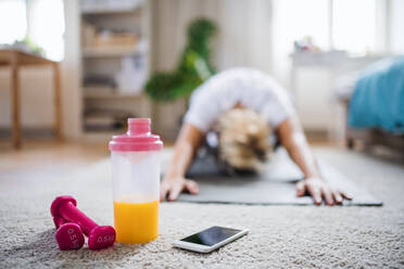 A young woman doing exercise on the floor indoors at home, front view. - HPIF27139