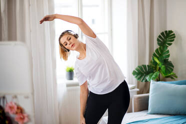 Eine junge Frau macht Übungen im Schlafzimmer zu Hause. - HPIF27144