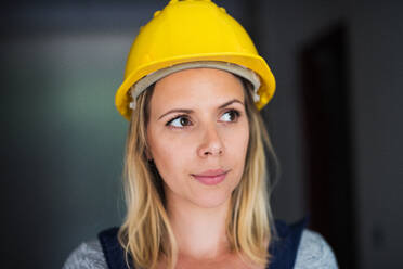 Porträt einer Arbeiterin auf der Baustelle, Nahaufnahme einer schönen jungen Frau mit gelbem Helm. - HPIF27240