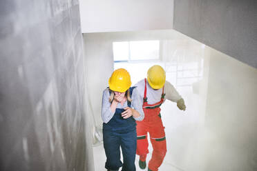 Woman and man workers running up the stairs at the construction site, coughing. - HPIF27258