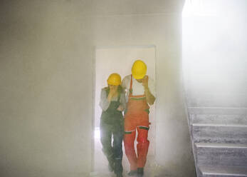Woman and man workers running out of the construction site, suffocating. Carbon monoxide poisonous gas cloud. - HPIF27259