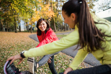 Zwei aktive Läuferinnen, die sich nach dem Lauf im Park in der herbstlichen Natur die Beine vertreten. - HPIF27296