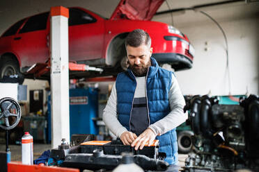 Älterer Mann, der ein Auto in einer Garage repariert. - HPIF27306