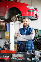 Portrait of a man mechanic in a car garage, arms crossed. - HPIF27309