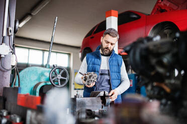 Mature man mechanic repairing a car in a garage. - HPIF27316